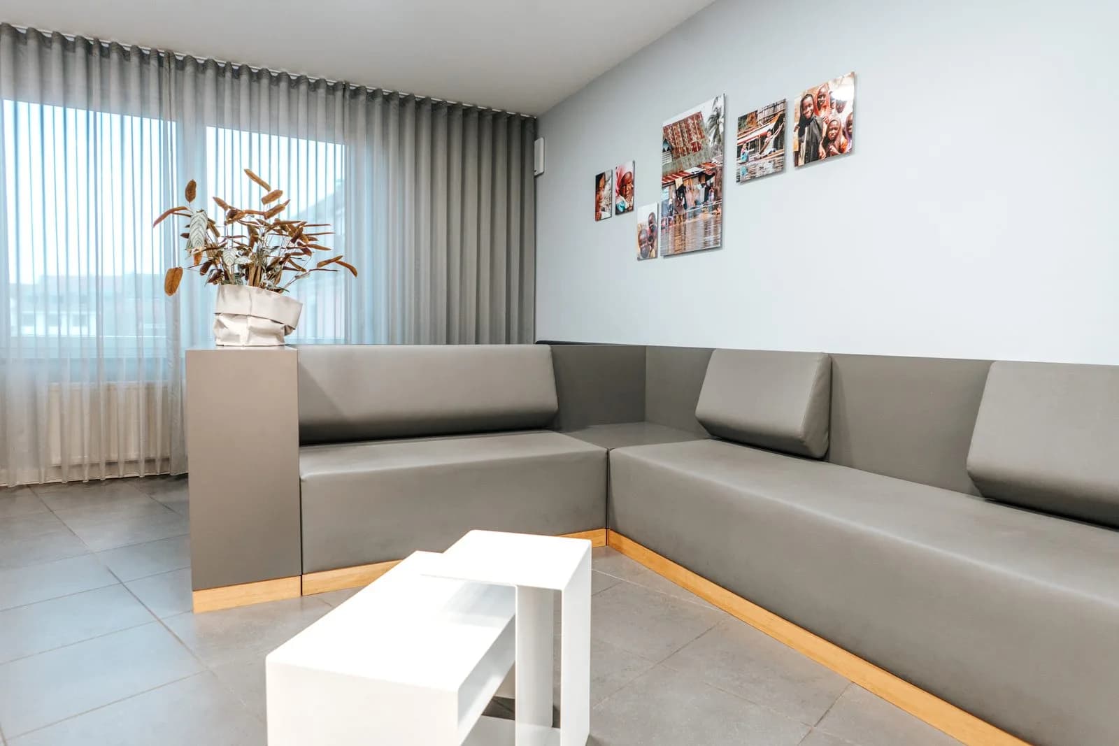 Wartebereich mit grauer Sitzecke und Bildern an der Wand